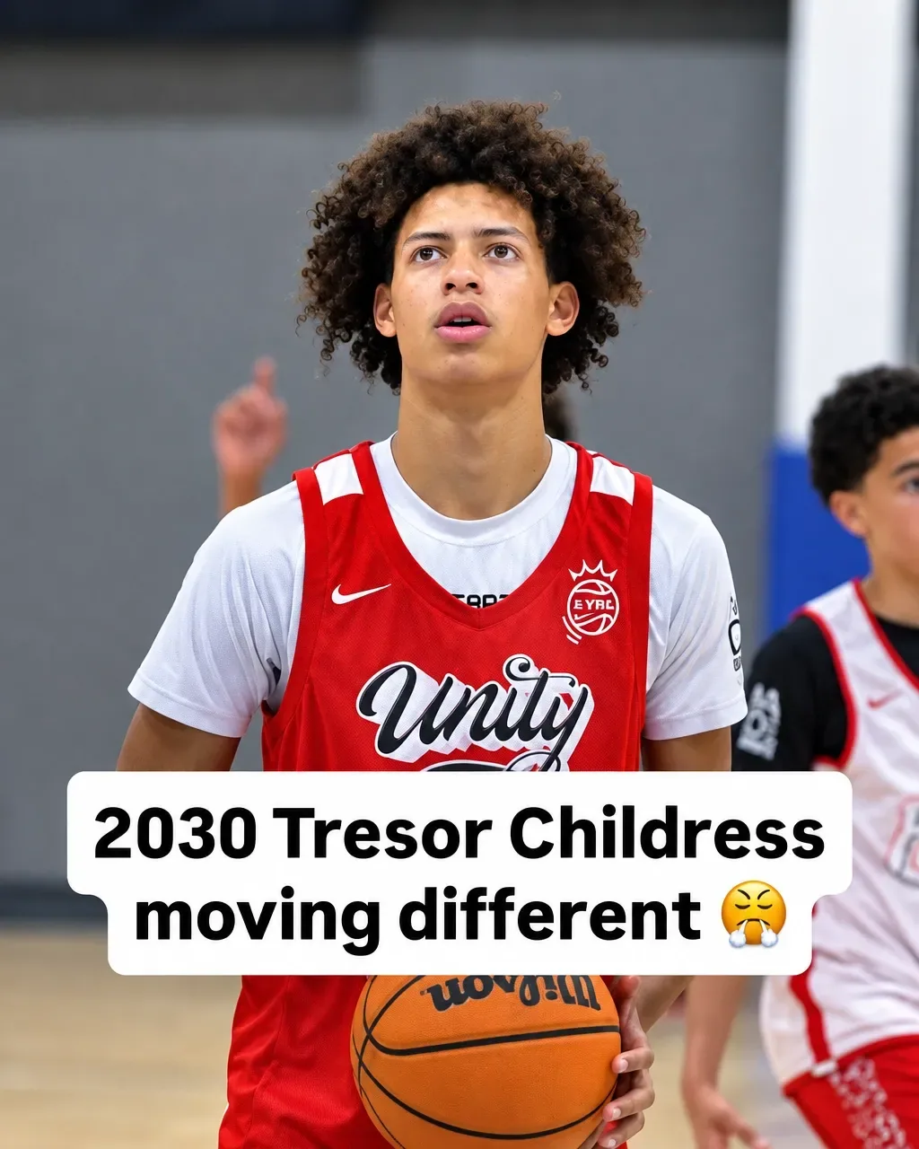 Tresor Childress holding the ball in a red Arizona Unity jersey